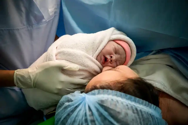 1716791392517-doctor-holding-baby-with-mother-hospital