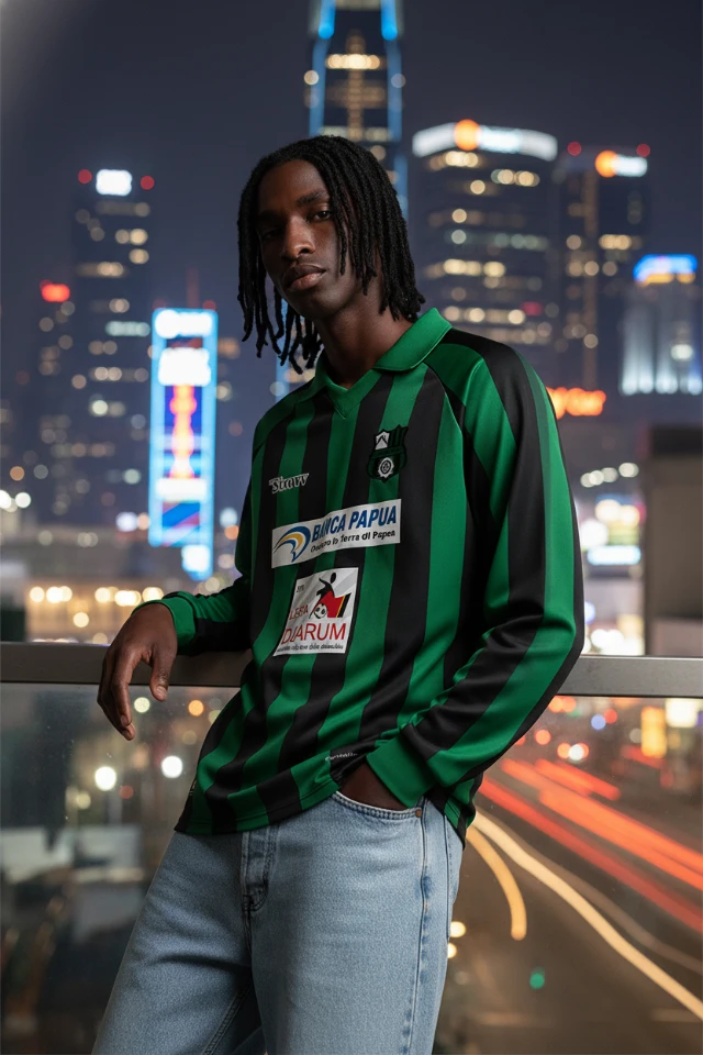 1765121218339-Jersey_Sepak_Bola_Lengan_Panjang_Garis_Hijau_Hitam_Retro_(AC_Wamena)_-_Dinamis___Era_90-an_Streetwear_(Tinggi)_-_Revisi__aku_butuh_pose_yang_berbeda_dengan_background_city_neon_light.webp
